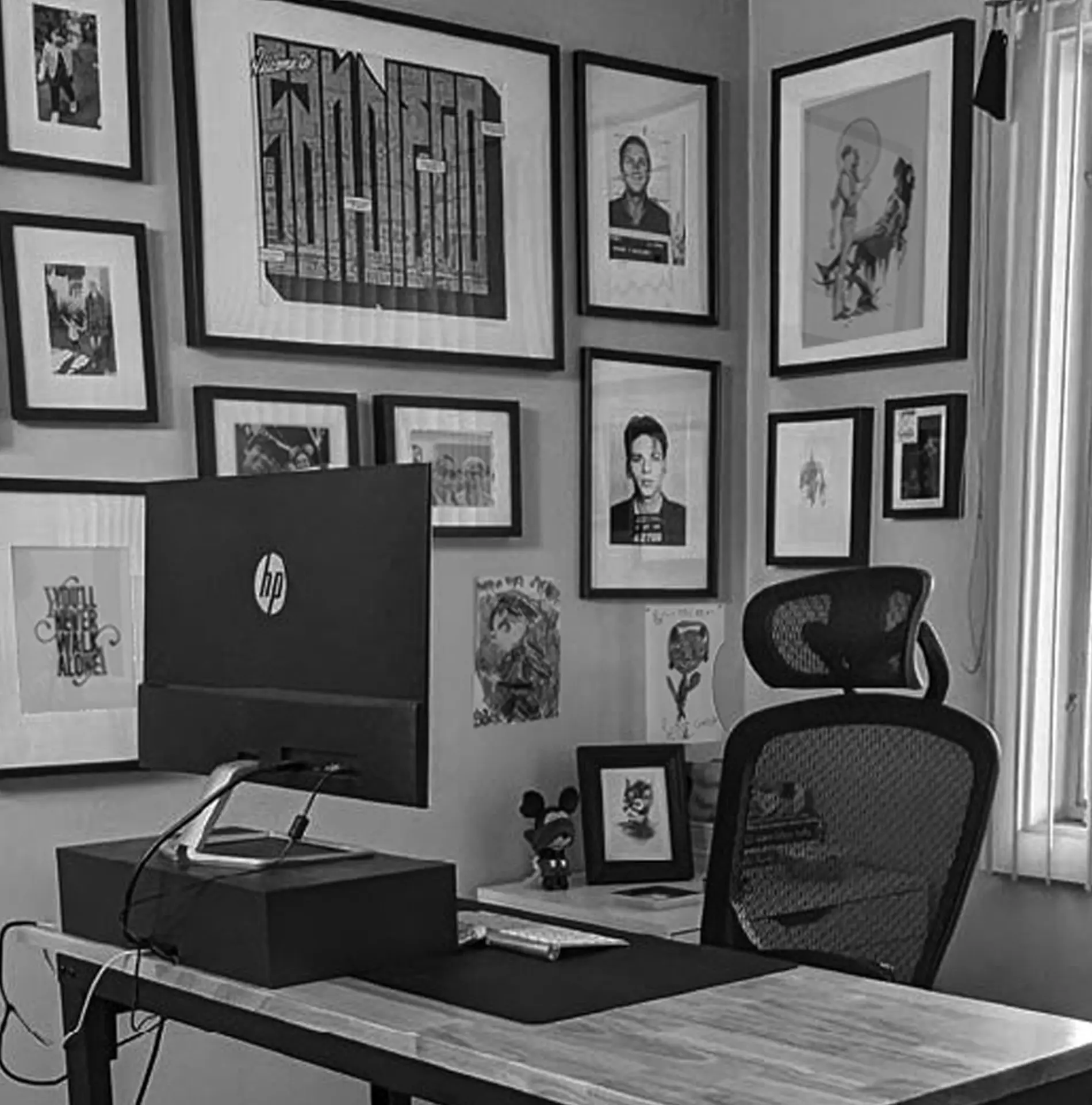 oh dang! office - desk with a computer monitor, and an open graphic design book and art prints on the wall adjacent to the desk