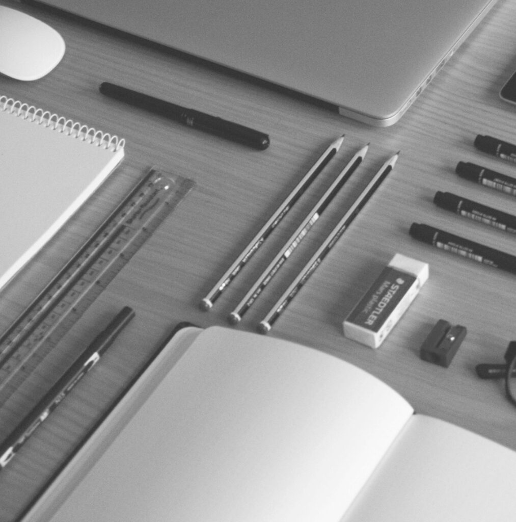 flat lay of pencils, sketchbooks, erasers, pens, ruler and macbook pro
